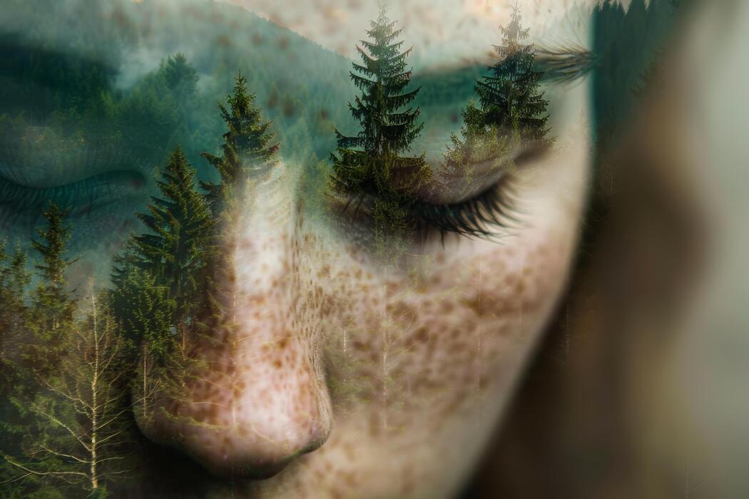 Double exposition poétique du visage d'une femme aux yeux fermés et d'une forêt de sapins, symbolisant le lâcher-prise, l'apaisement de la surcharge sensorielle et la reconnexion à soi à travers les soins corporels énergétiques d'Un Souffle d’Art-Mot-Ni